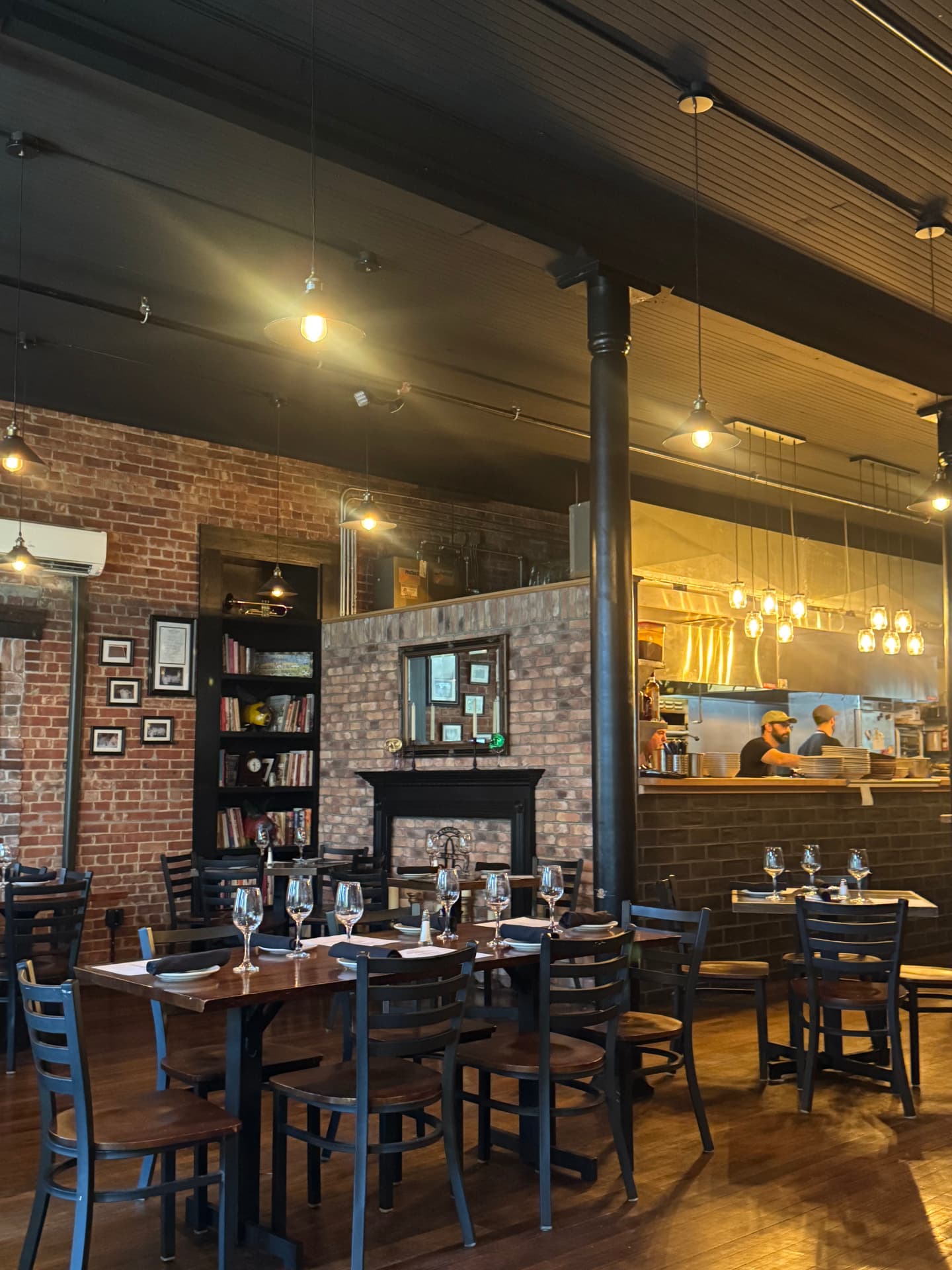 Drew’s Bayshore Bistro dining room with exposed brick, a fireplace and an open kitchen