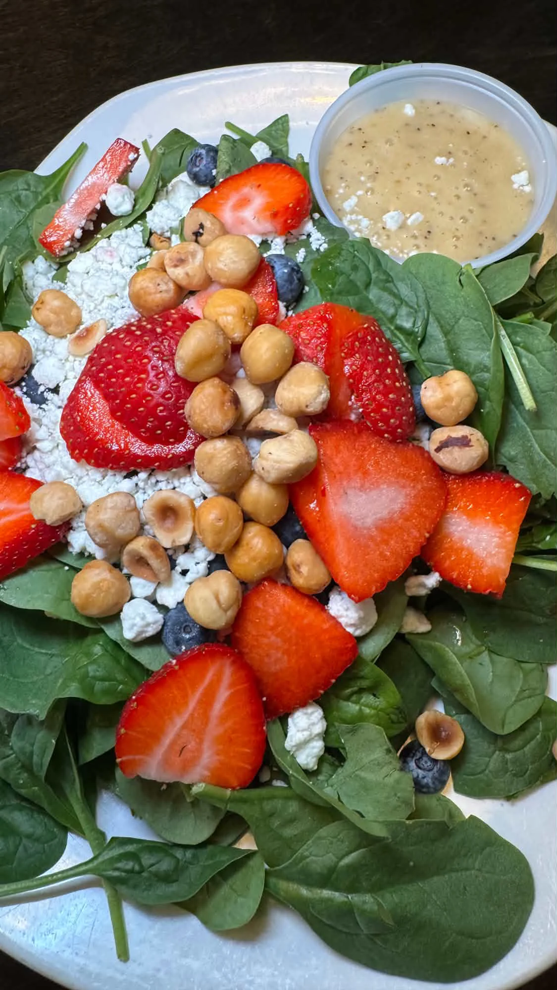 Spinach salad with strawberries, blueberries, crumbled cheese and toasted nuts at Zoni’s