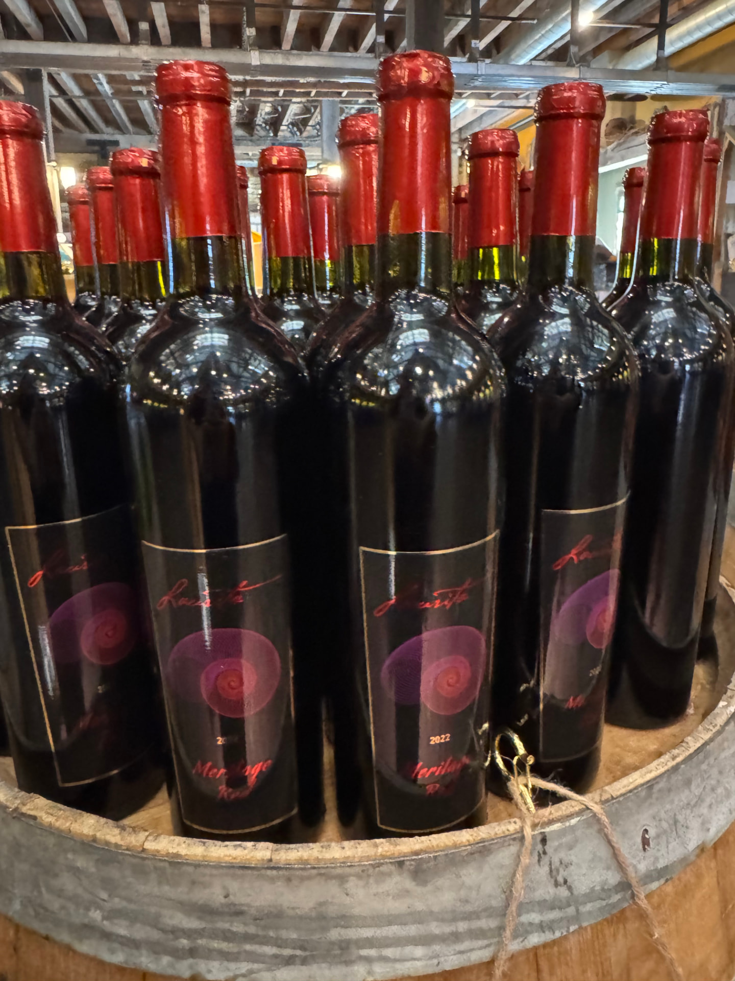 Laurita wine bottles with red foil tops displayed on a barrel